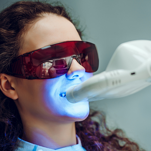 Female patient receiving teeth whitening in dental chair