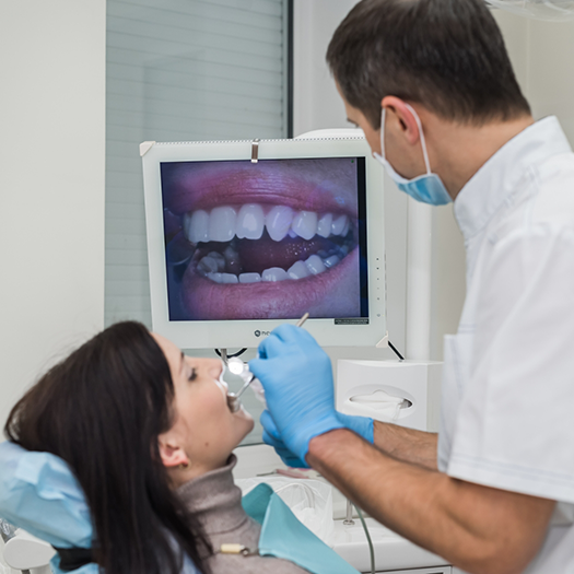 Dentist putting intraoral camera in patients mouth and looking at monitor