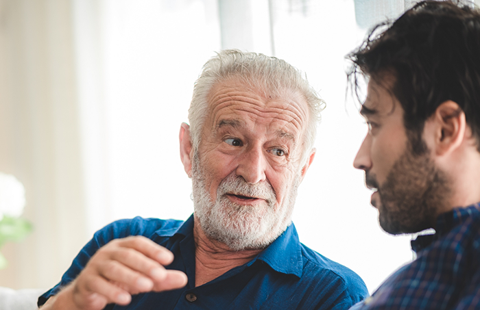 Senior man in blue shirt talking to another man