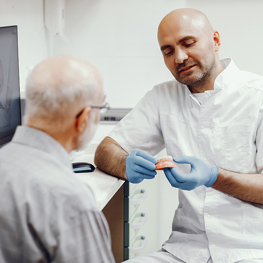 Dentist showing senior man a full denture