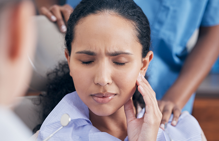 Woman visiting emergency dentist in Fort Smith and touching jaw in pain