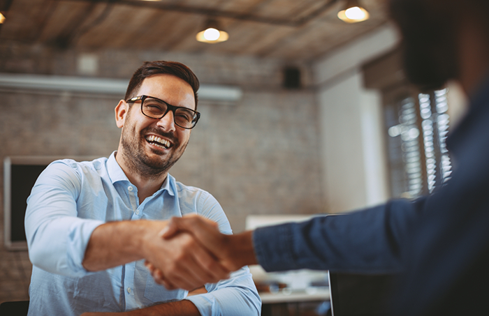 Man with glasses shaking dental team members hand