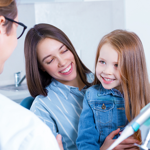 Woman with little girl sitting on her lap in dental chair