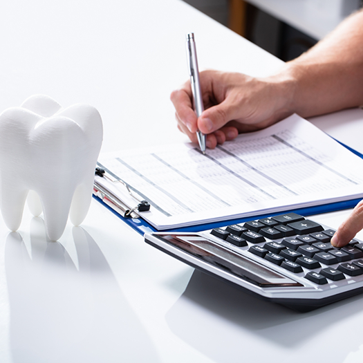 Close up of insurance form on clipboard calculator and tooth