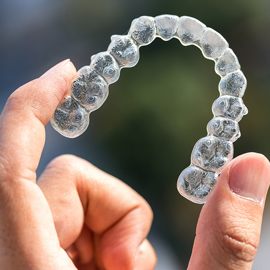 Close up of hand holding a clear aligner