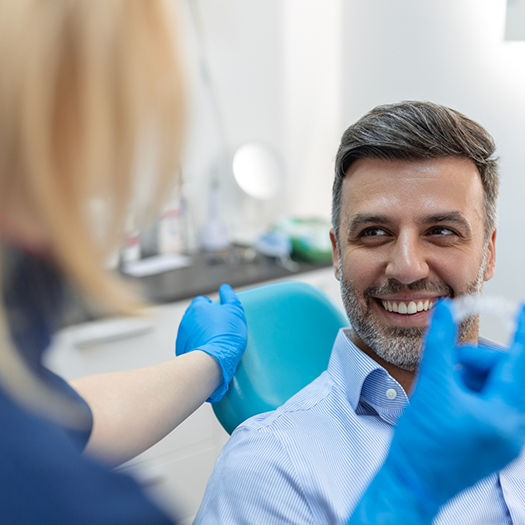 Smiling man in dental chair talking to female dentist