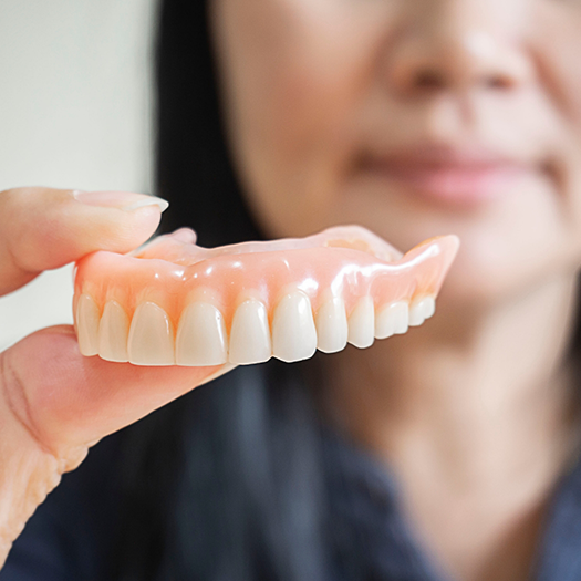 Close up of woman holding a denture