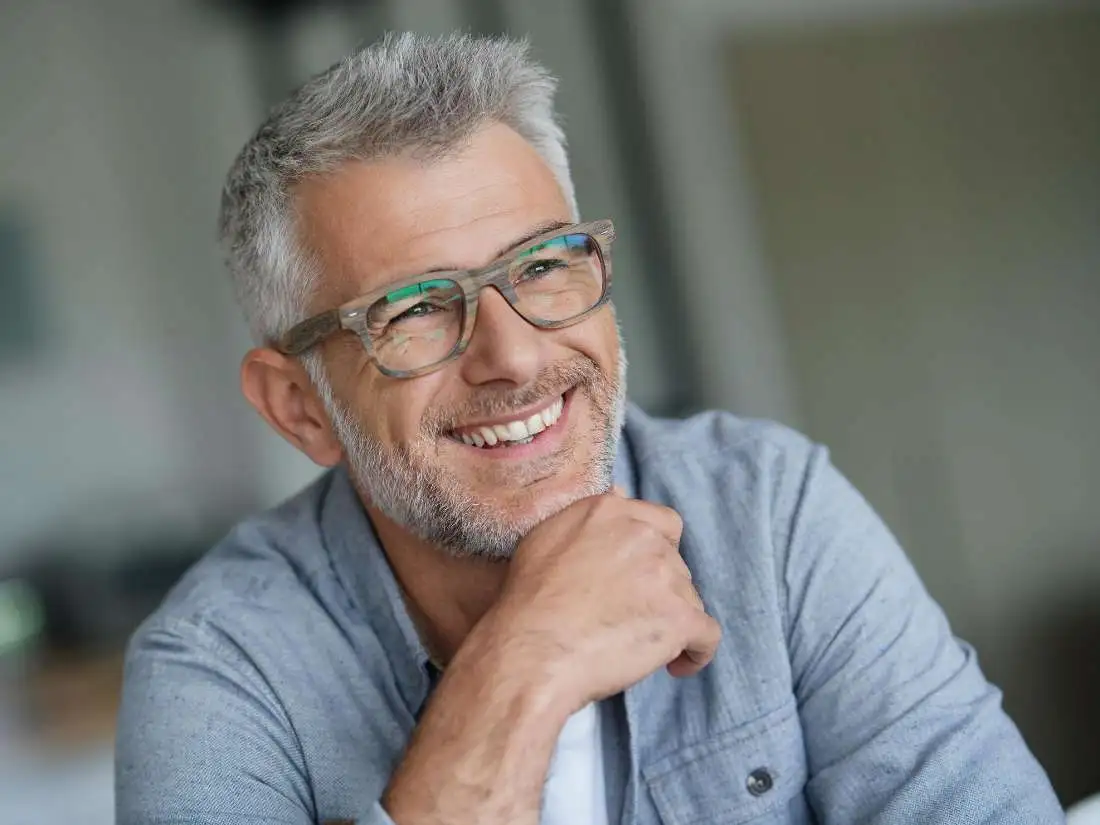 Man with grey jacket and glasses smiling