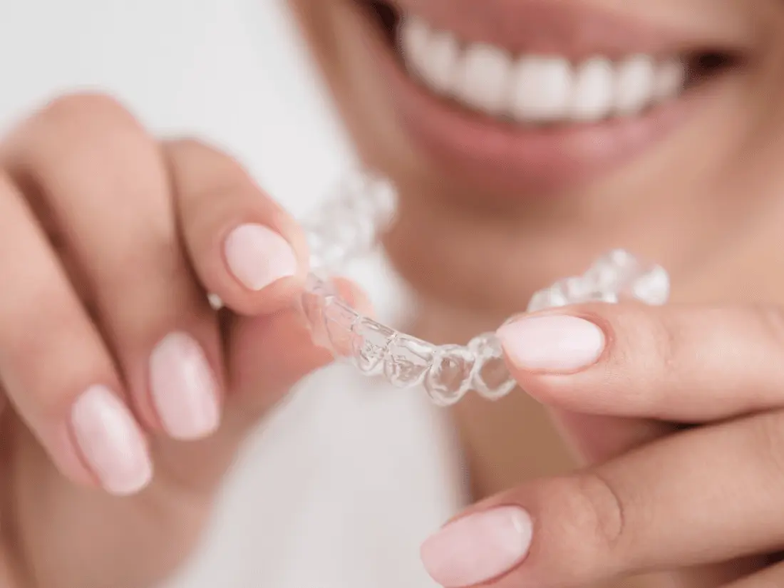 Smiling woman holding a clear aligner