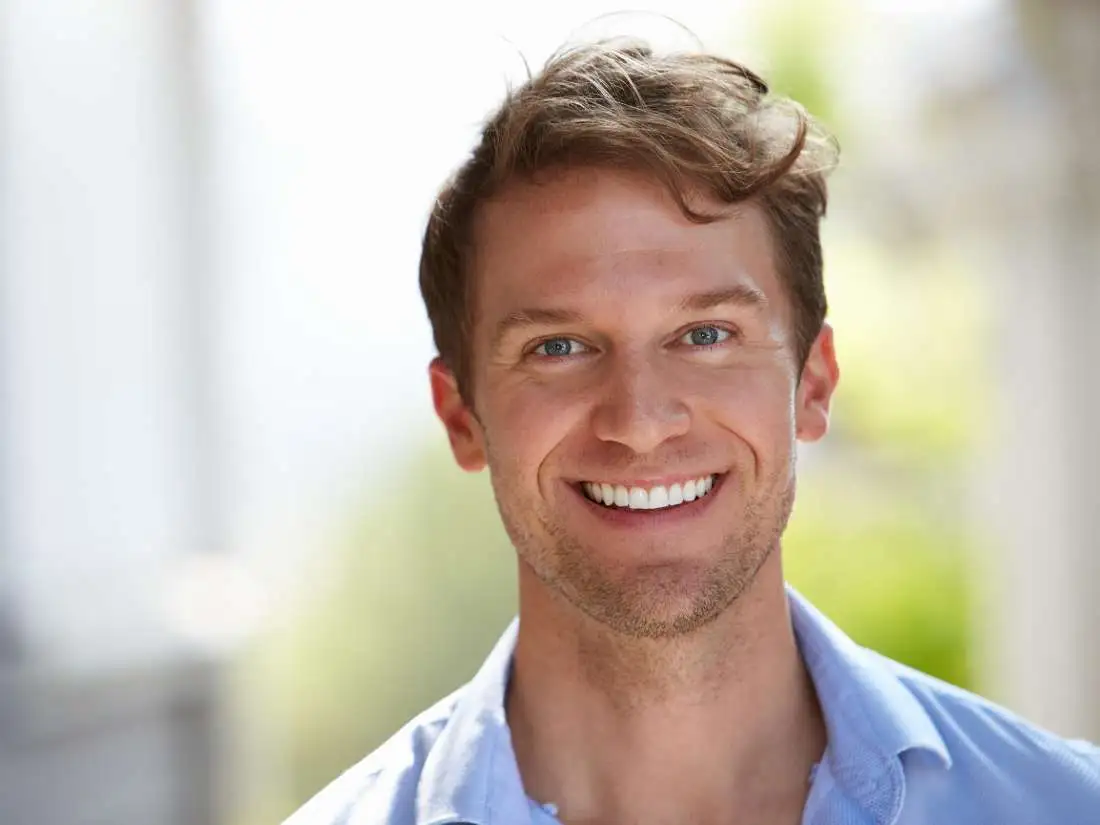 Man in collared shirt smiling outside