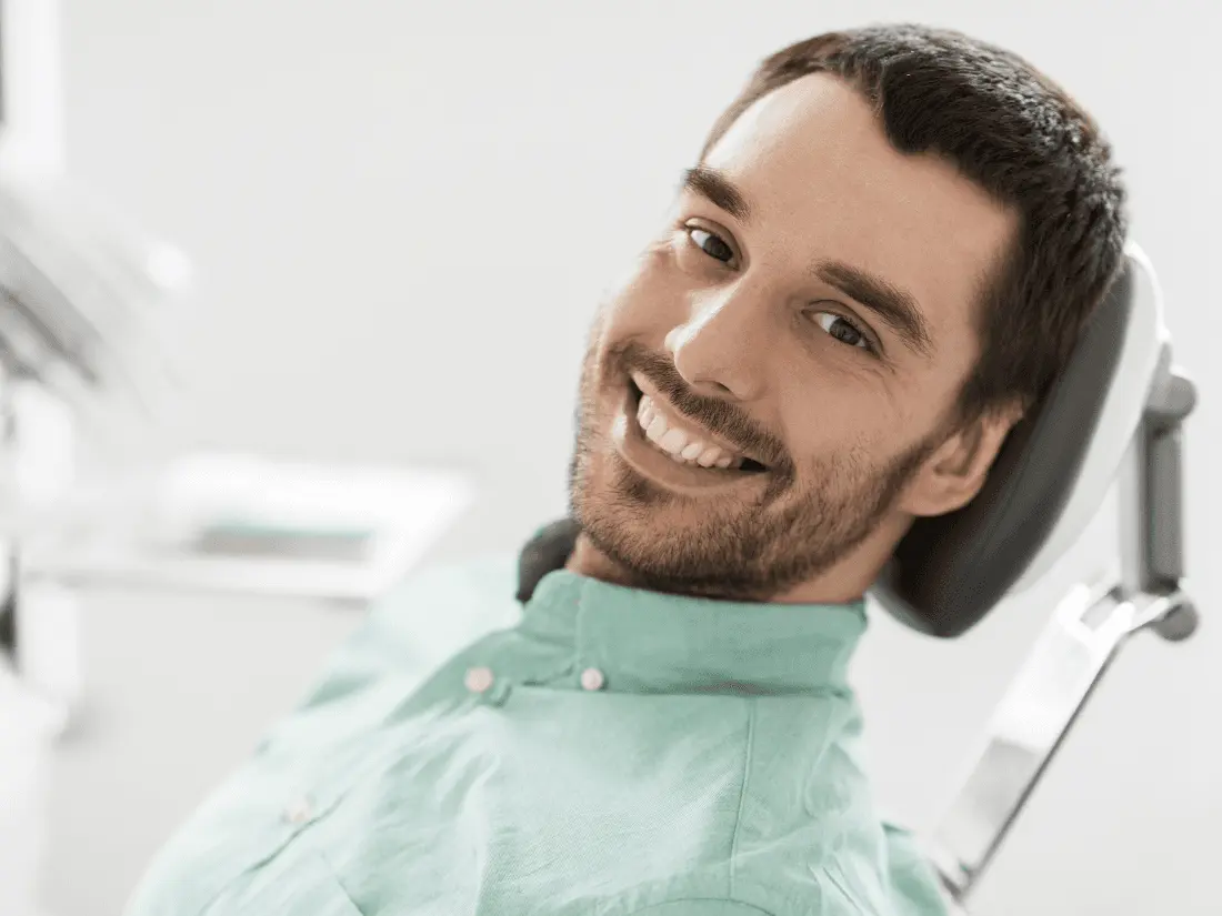 Bearded man leaning back in dental chair and smiling