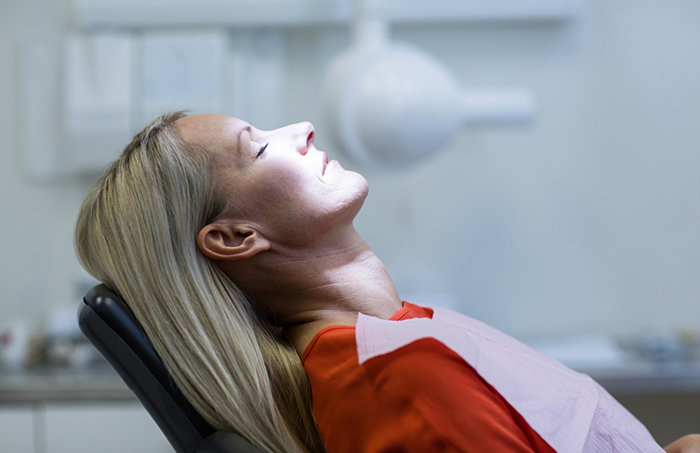 Woman in red shirt relaxing in dental chair