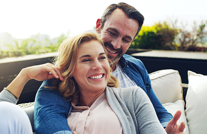 Man on couch looking down at woman and smiling