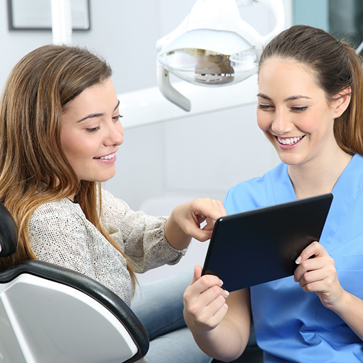 Dentist holding tablet and patient pointing to it