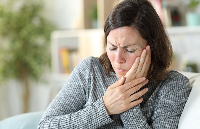 Woman in grey sweater with jaw pain