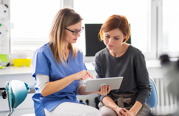 Female dentist showing patient something on a tablet