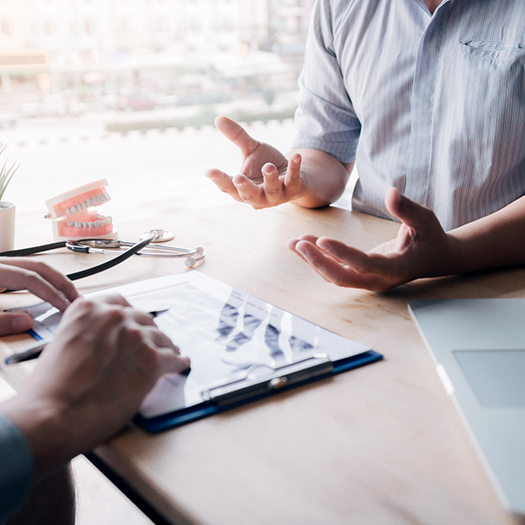 Two people talking over desk with clipboard